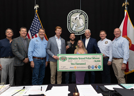 Winner of 2025 Florida Python Challenger holding check with FWC Commissioners 